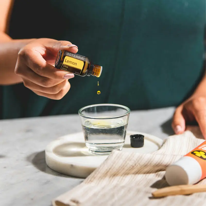 image showing person pouring lemon drop in glass of water