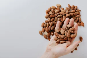 Unrecognizable man taking almonds from white desk